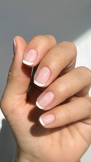 Hand with short french tip manicure