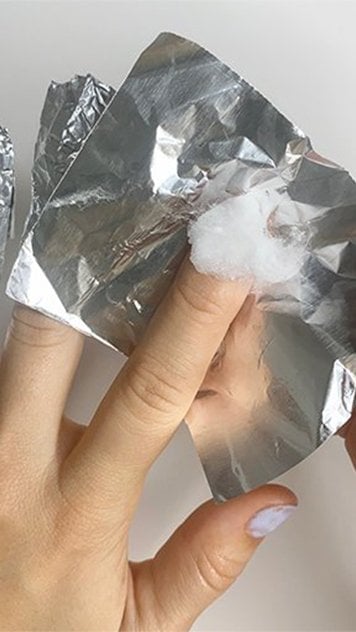 Light skin hands, one with 3 fingertips wrapped in foil, the 4th being wrapped over a cotton ball