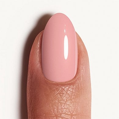Light skin fingertip with nail painted in beige-pink ‘topless & barefoot’ essie polish
