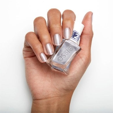 Hand holding a bottle of Essie nail polish, with fingers painted in a metallic chrome shade.